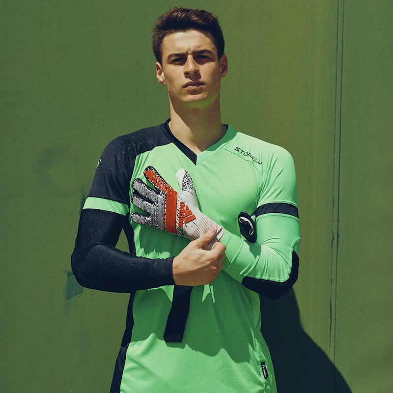 goalkeeper in neon jersey leaning against wall with gloves