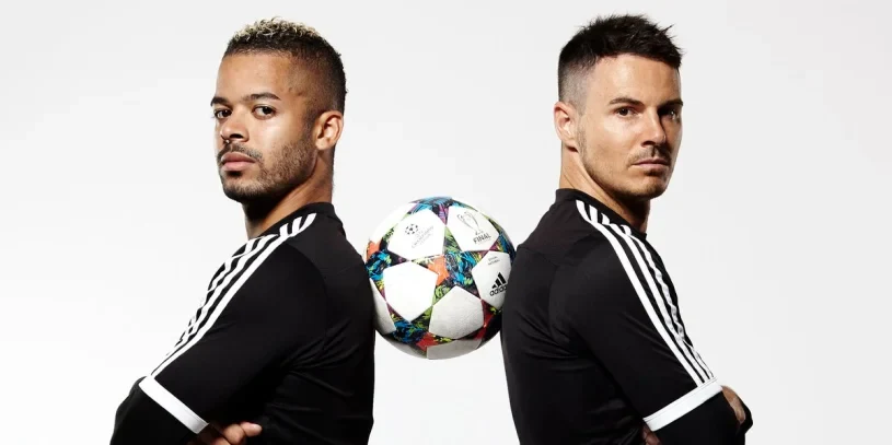 two soccer influencers back to back with ball between them